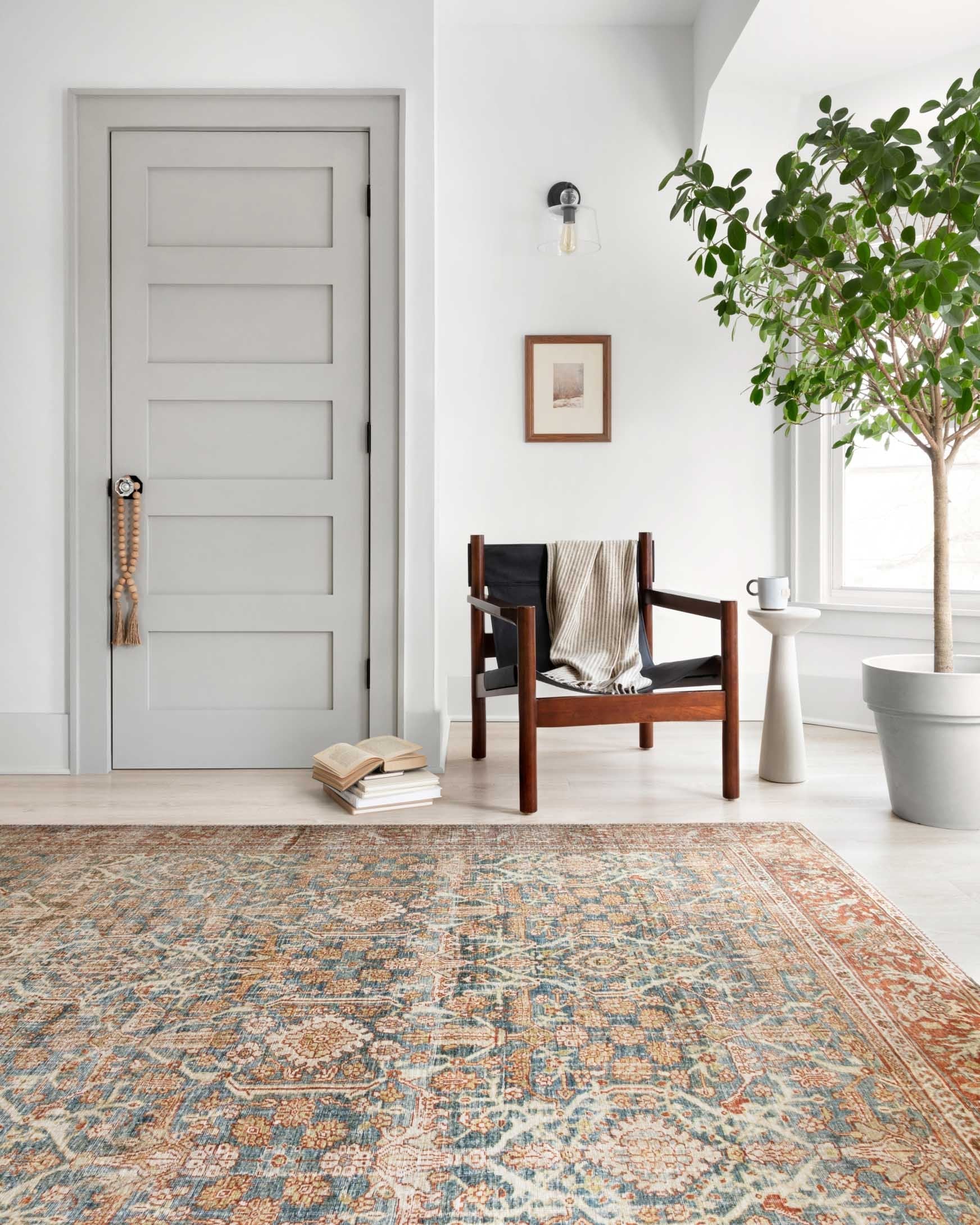 Ornate traditional rug laid in a room, blue center with rust and cream detailing.