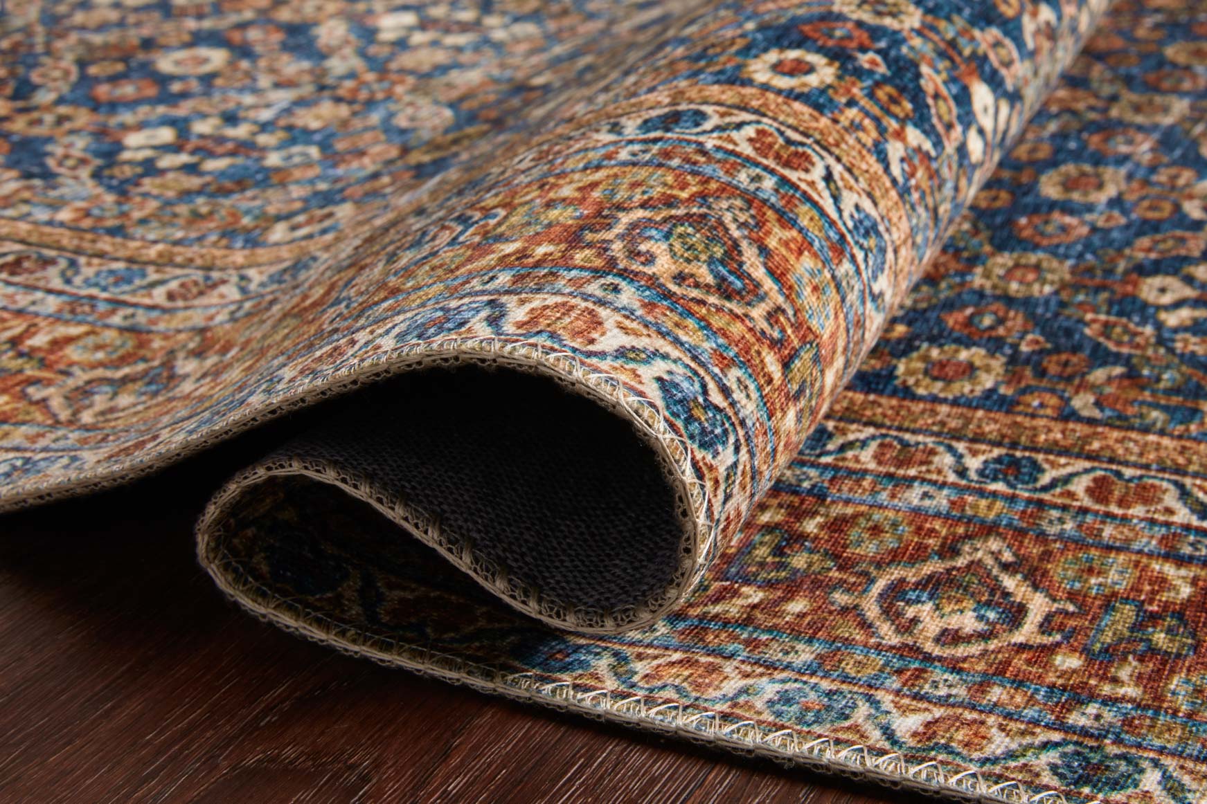 Cobalt blue rug rolled edge showing texture and underside fabric with patterned trim.