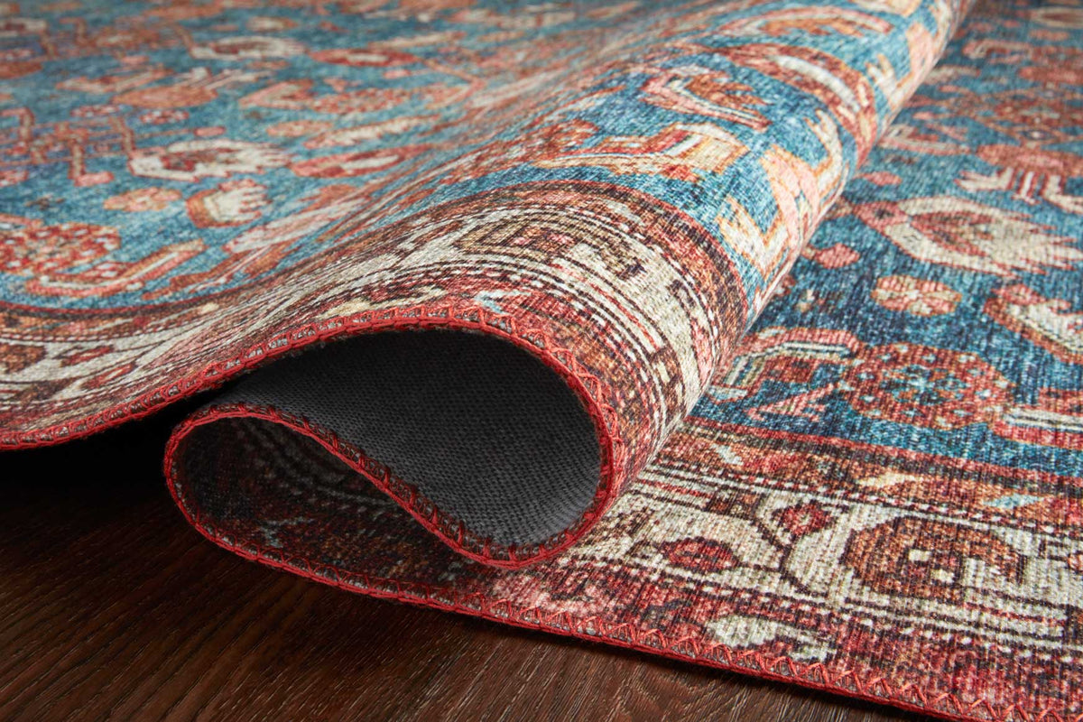 Traditional power-loomed rug rolled edge showing marine blue and clay red woven pile