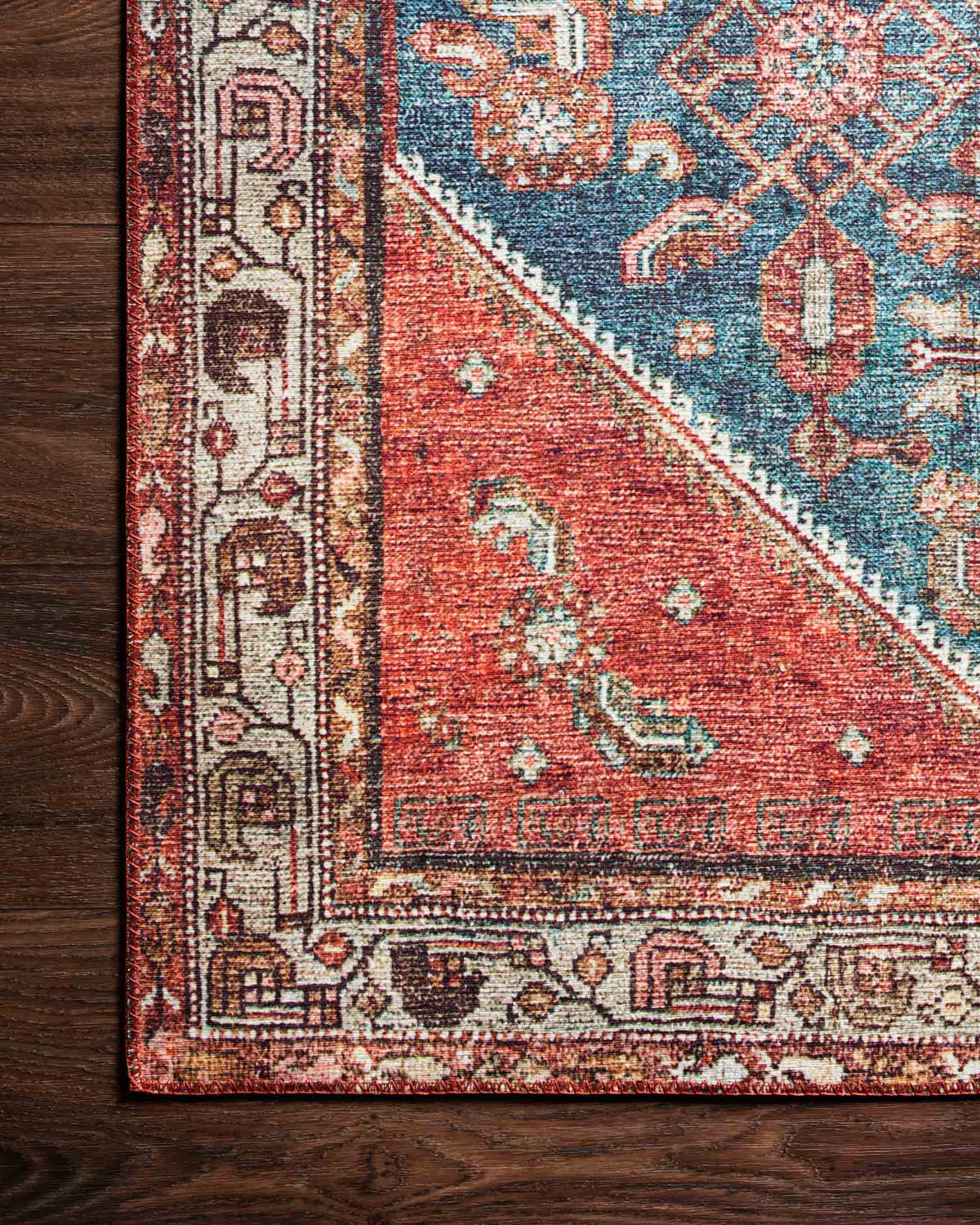 Traditional power-loomed rug close-up with marine blue field and clay red diagonal panel