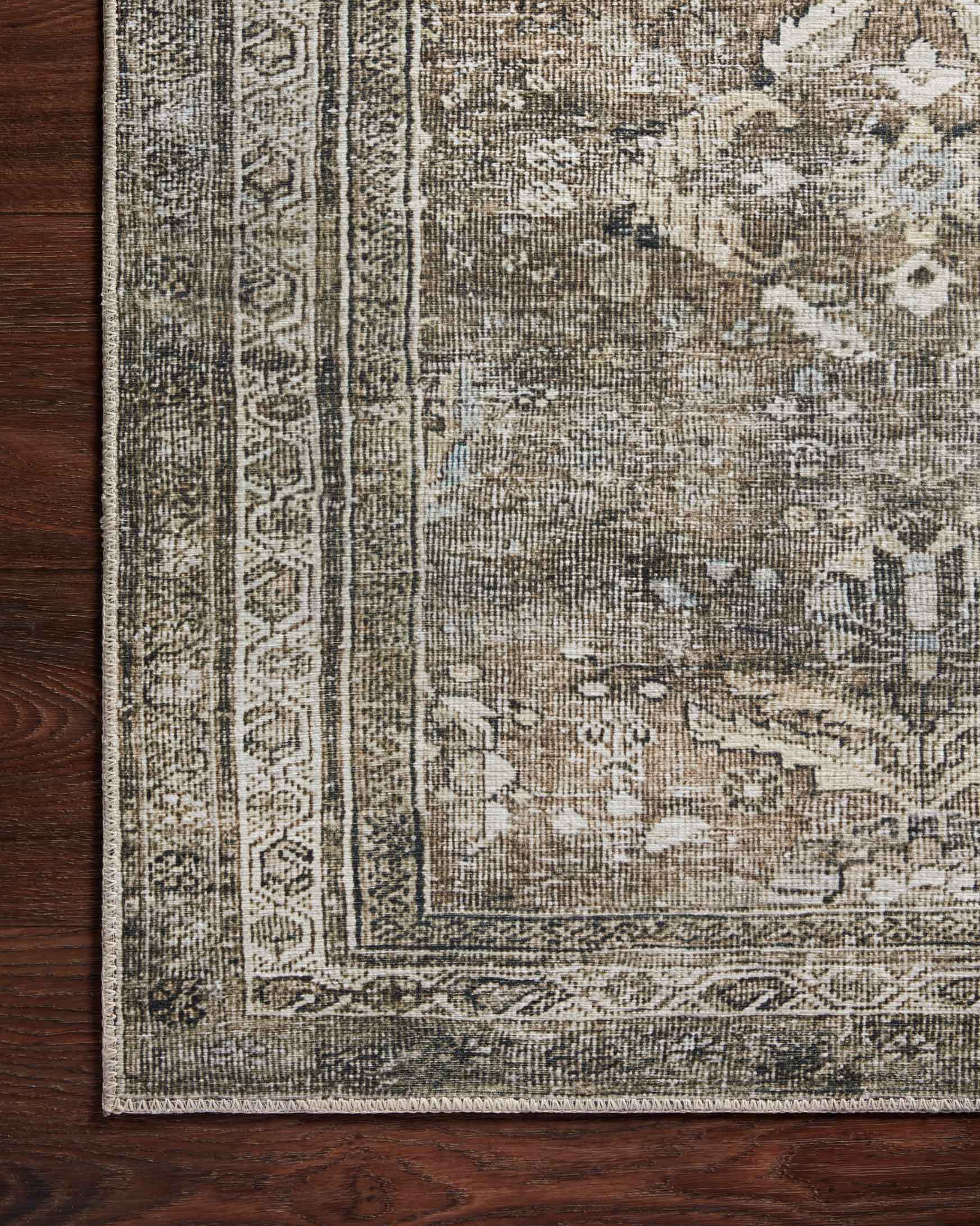 Corner close-up of antique grey rug with medallion motifs and decorative border.