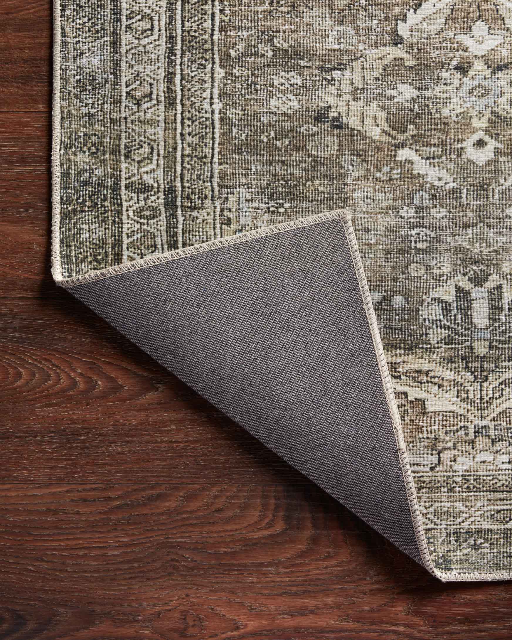 Rug edge with grey backing visible under an antique grey patterned surface.