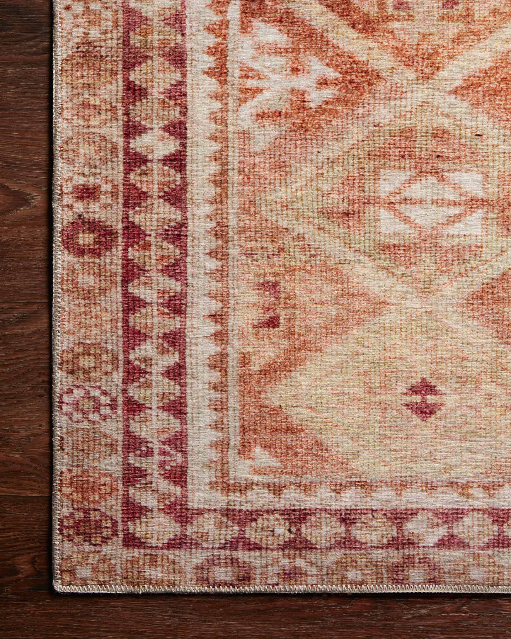 Corner detail of natural beige rug with spice red-brown border and geometric medallion lines.