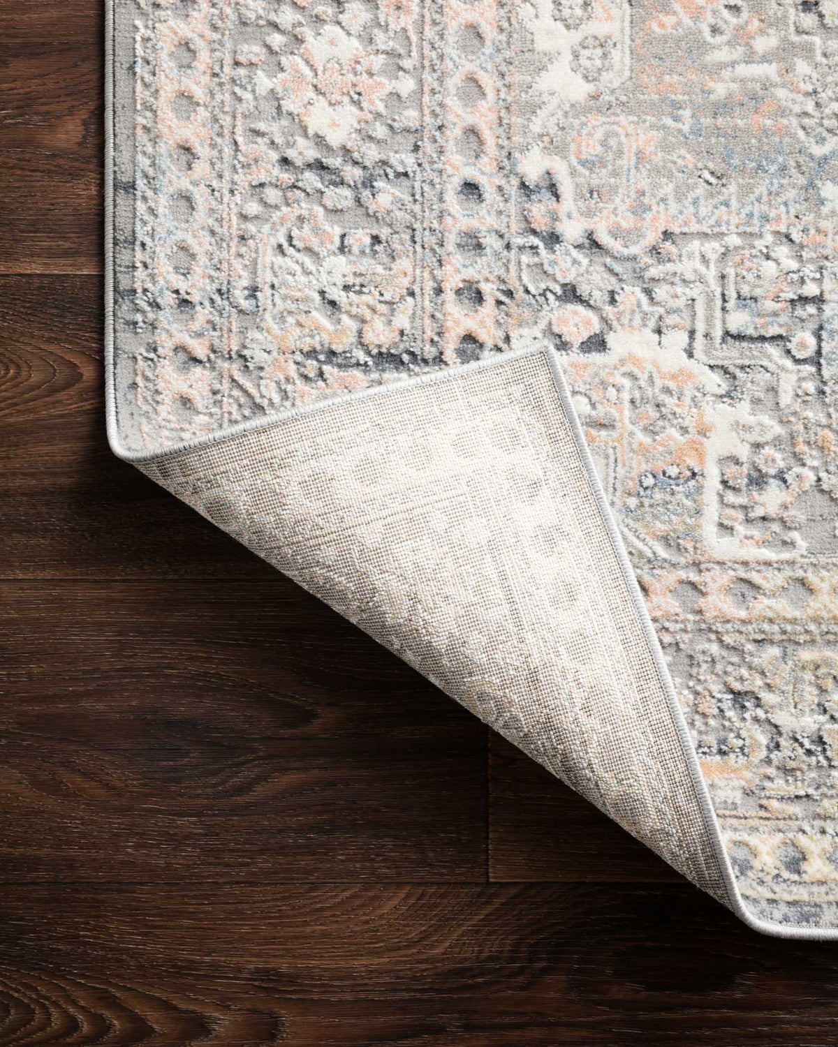 Light grey rug edge lifted to show woven underside and textured construction