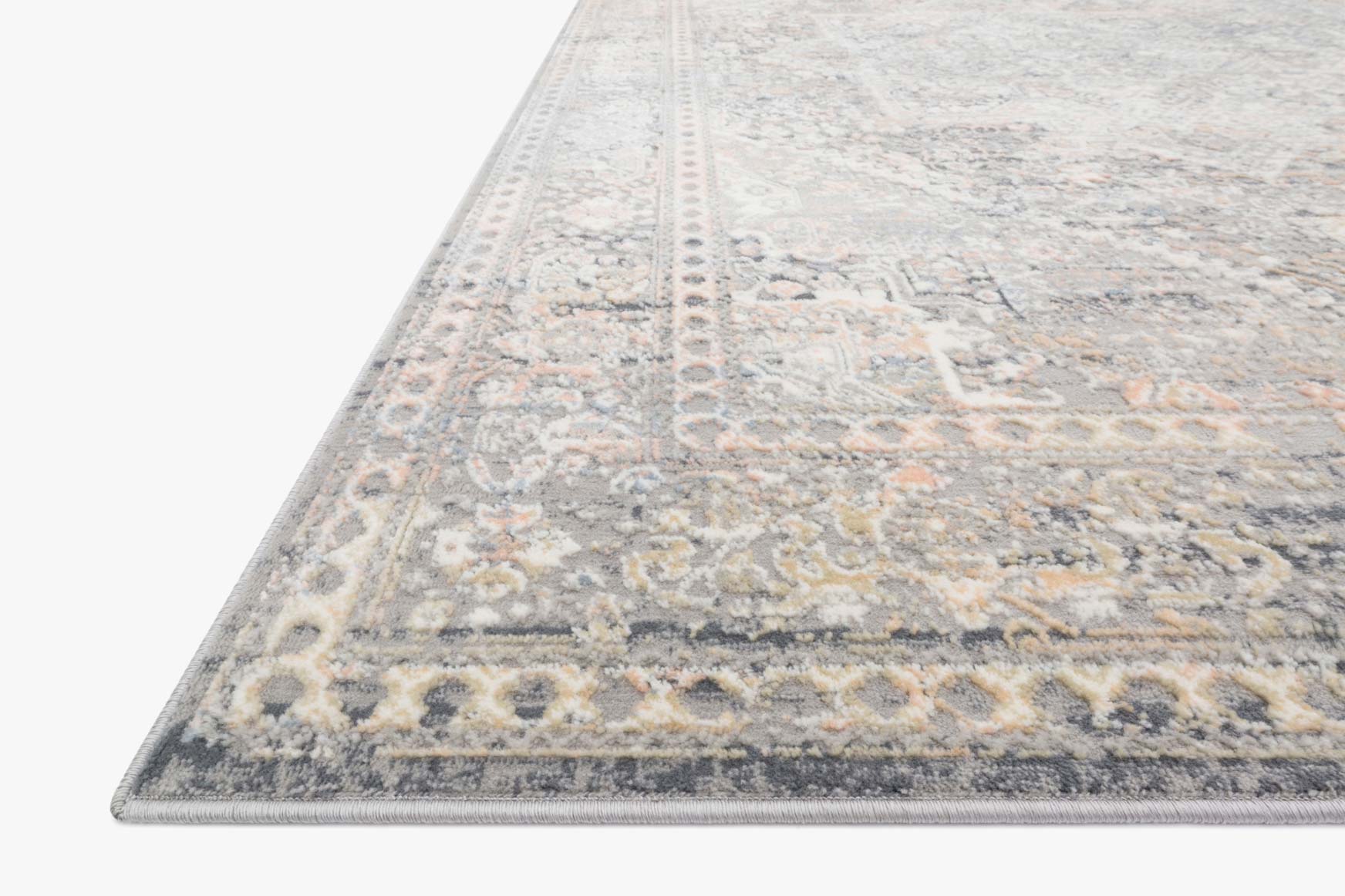 Corner close-up of light grey rug with detailed medallion pattern and border trim