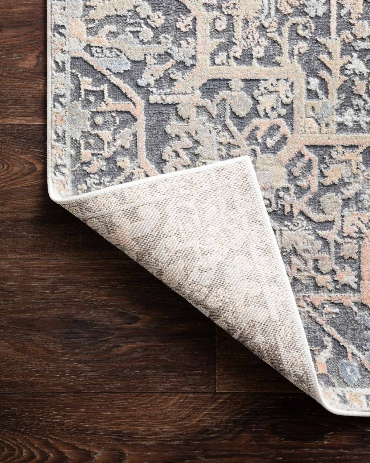 Power-loomed rug corner showing backing edge; charcoal blue and beige distressed pattern