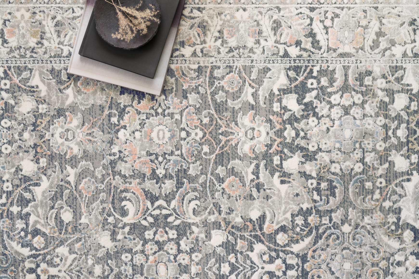 Close-up of grey and mist rug with intricate scrolling patterns and floral accents.