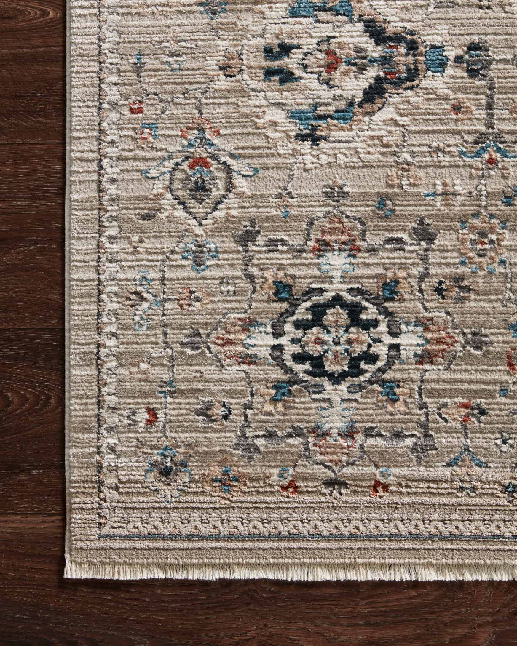 Power-loomed rug border close-up with dove field, teal floral medallion, and short fringe.
