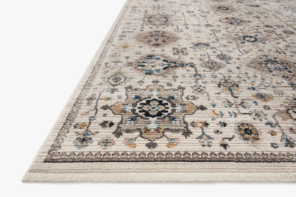 Ivory power-loomed rug with teal and navy distressed motifs, short fringe edges.