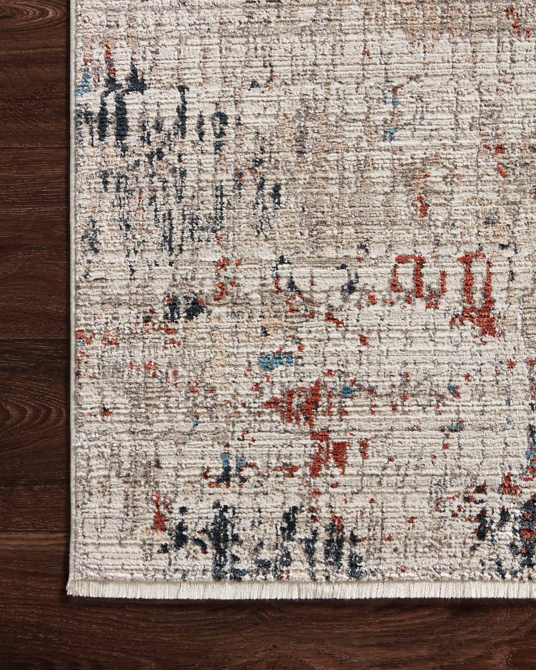 Ivory power-loomed rug close-up with distressed multicolor abstract texture and bound edge