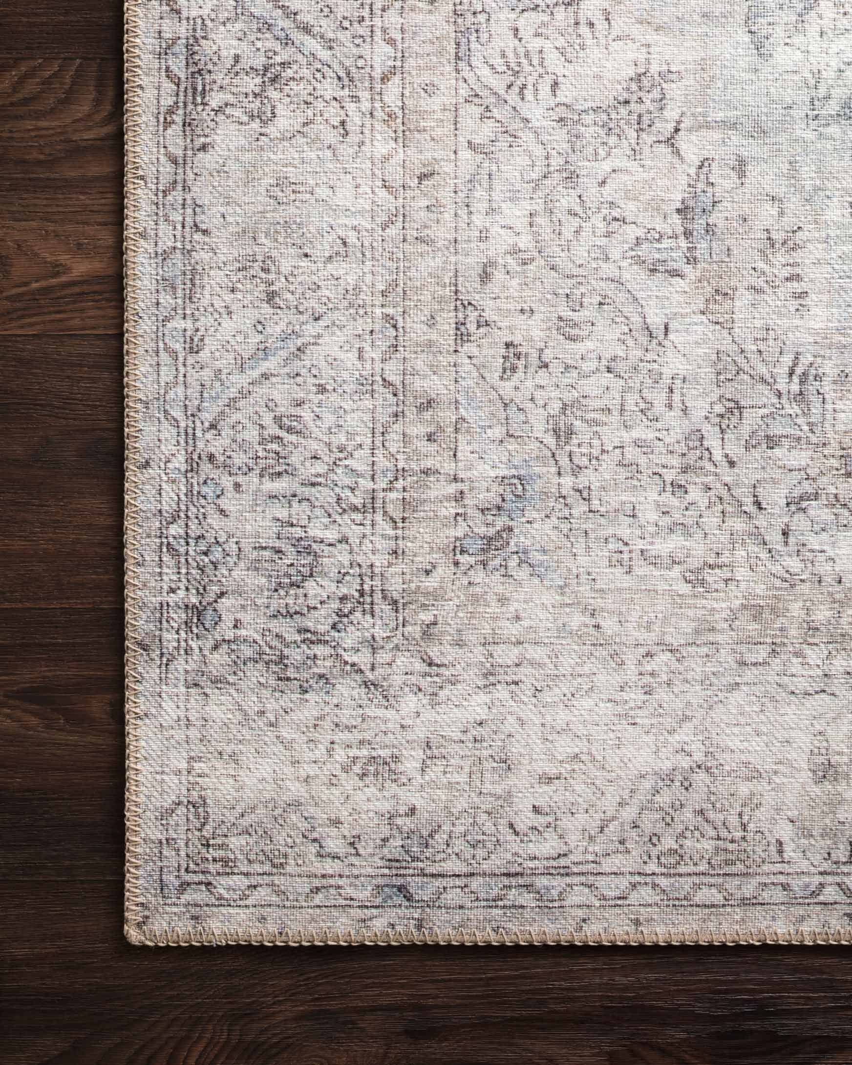 Silver and slate rug with patterned border and textured woven surface along one side.
