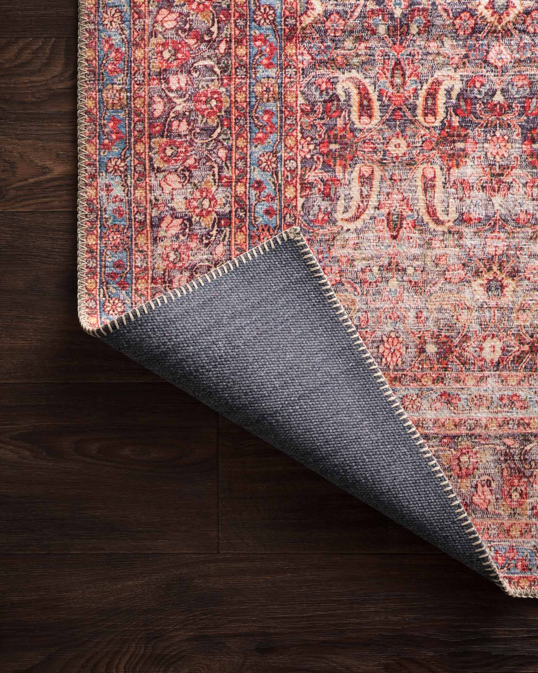 Traditional rug corner lifted to show backing fabric in gray-blue