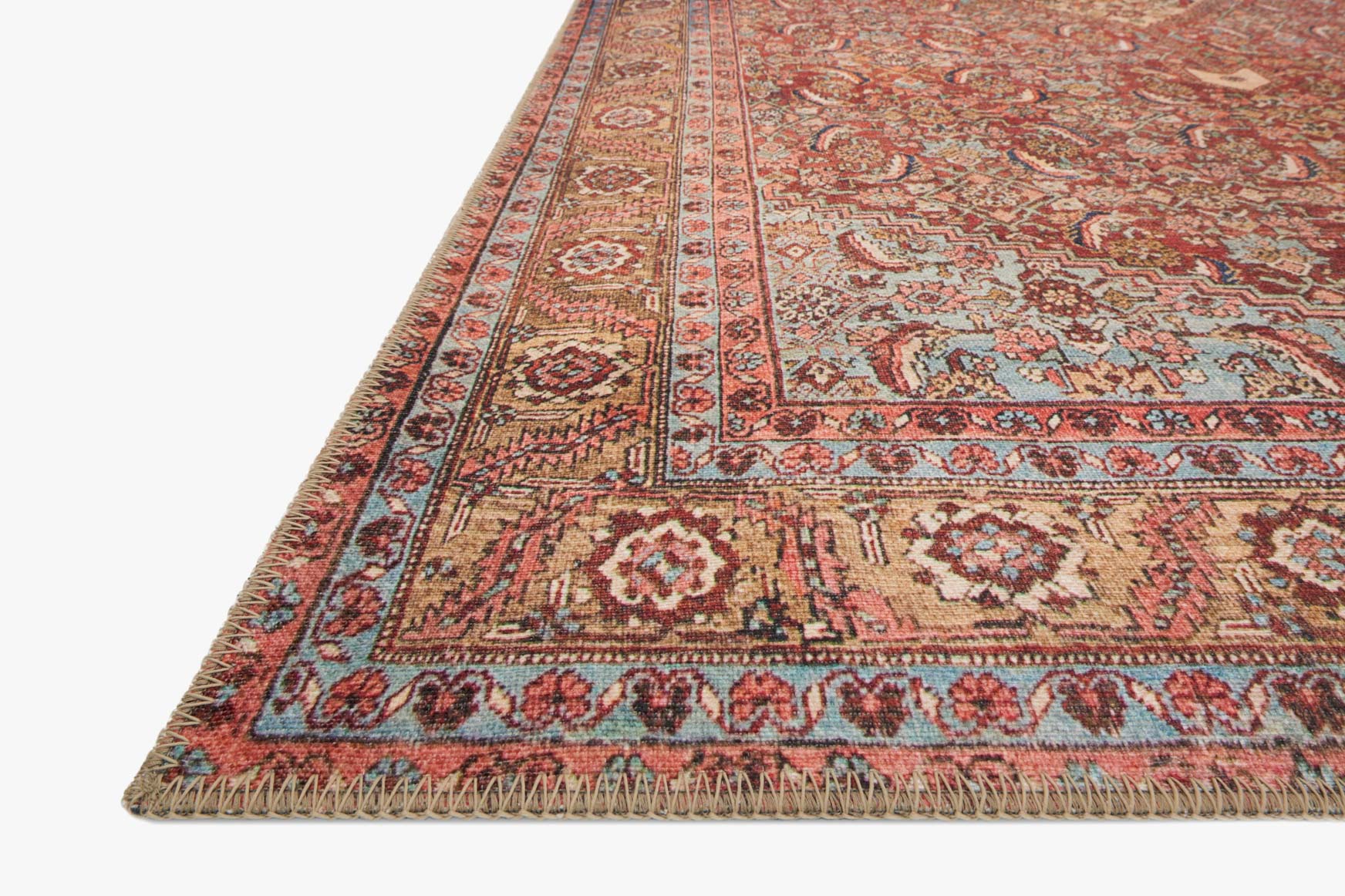 Corner view of red patterned rug with fringed edge and detailed medallion border