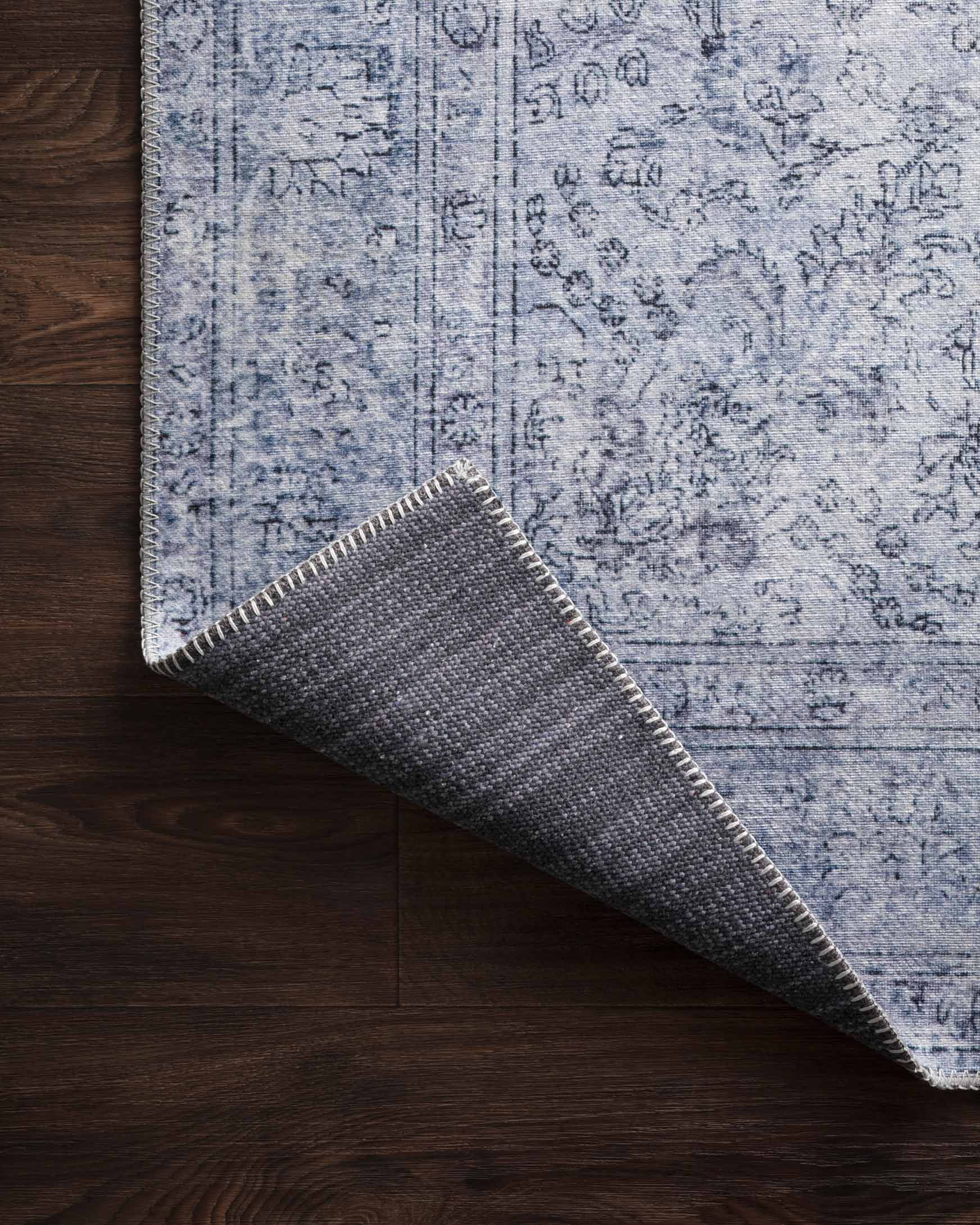 Slate blue rug rolled corner with dark gray backing and stitched fringe