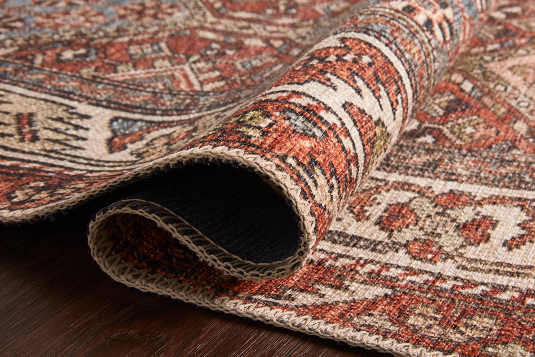 Close-up of spice red rug edge with fringed yarn and woven geometric pattern