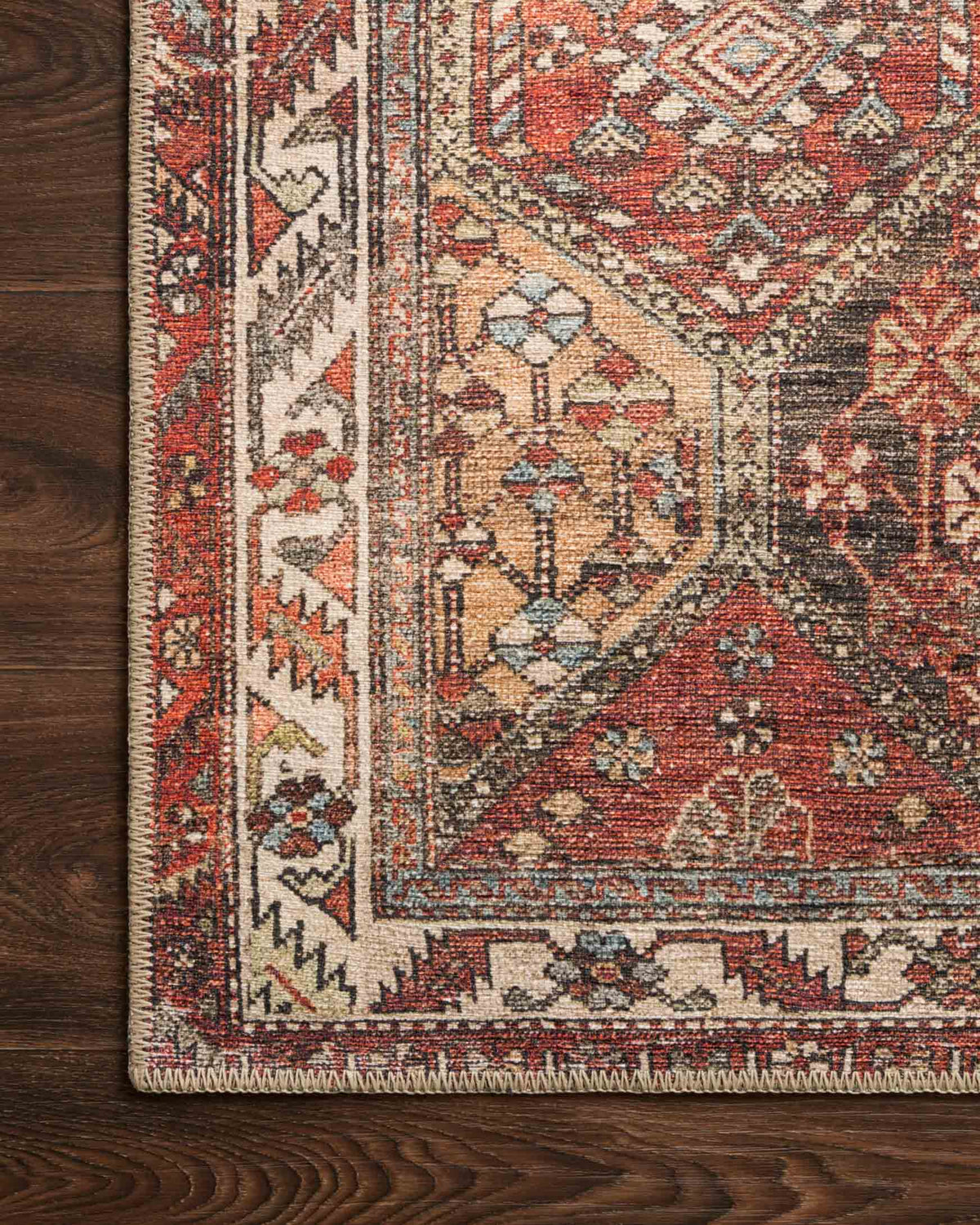 Close-up rug corner showing geometric motifs, striped border, and dark backing