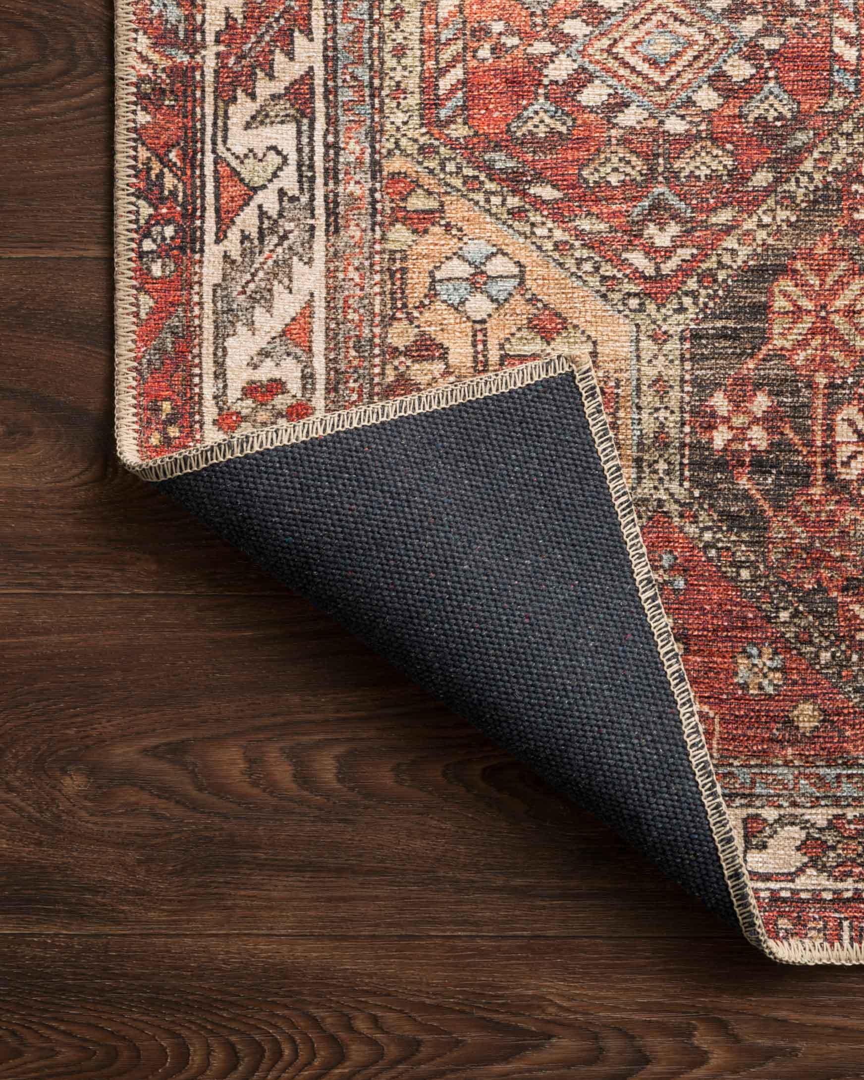 Rug corner close-up with dark backing underside and multicolor geometric border
