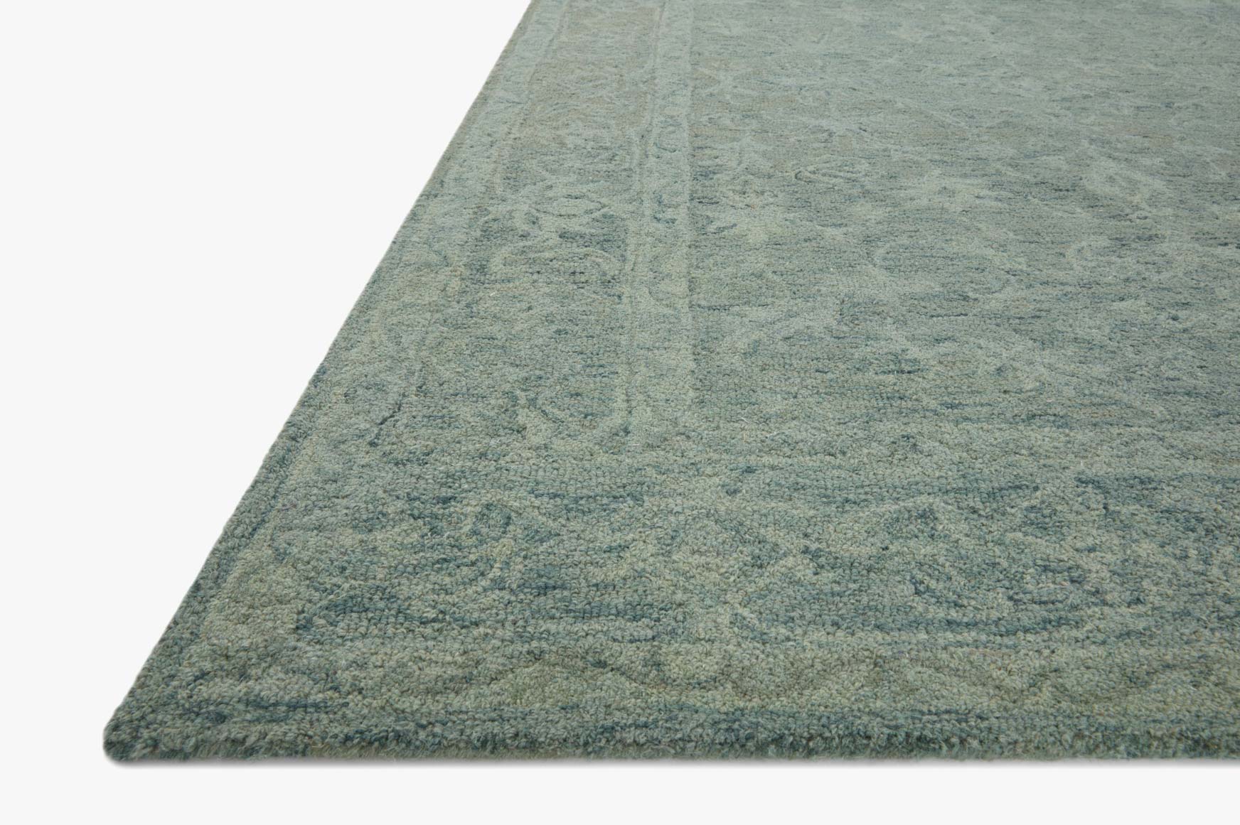 Teal hooked rug corner with textured cut-pile and subtle floral pattern
