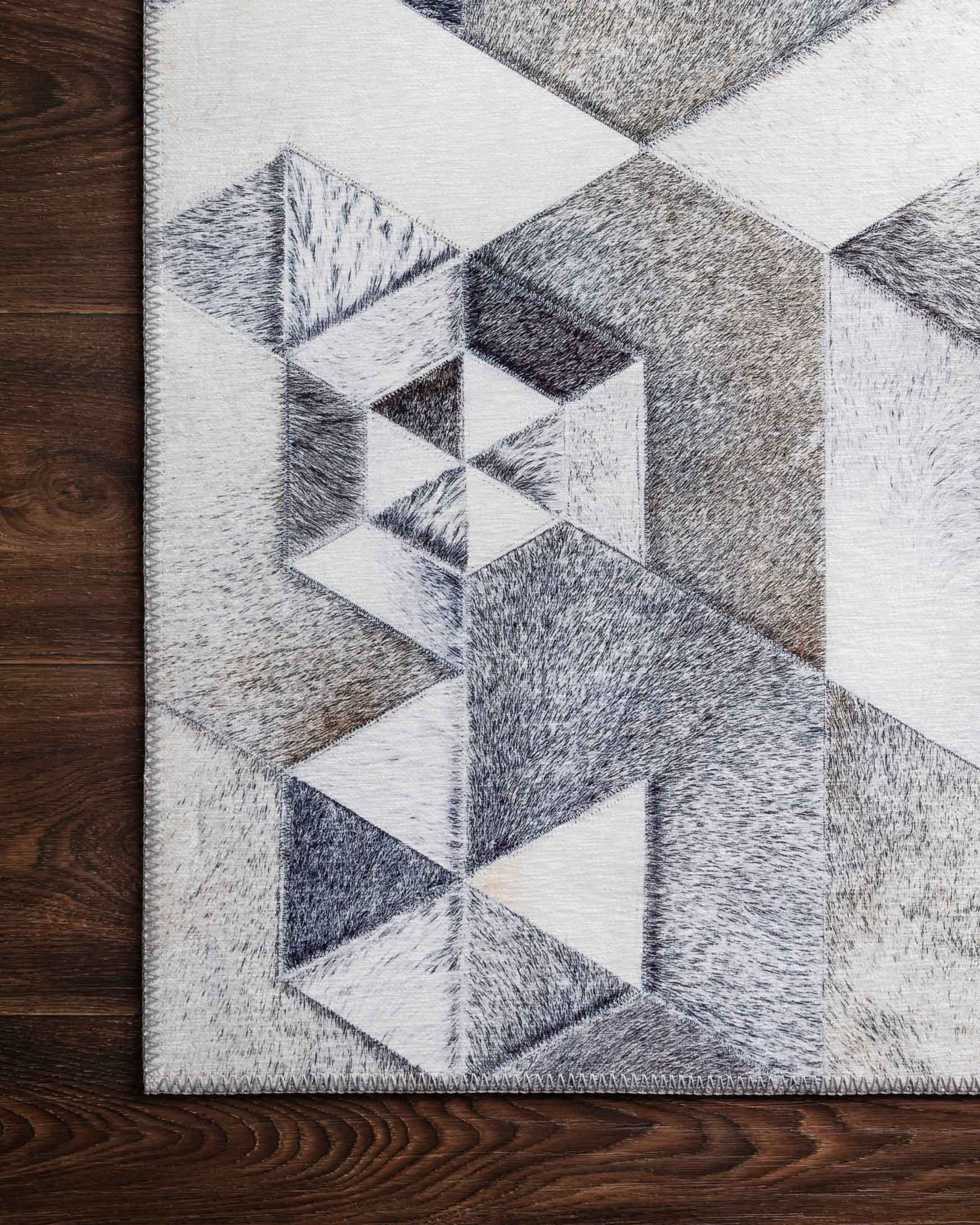 Close-up of grey and ivory rug surface showing detailed cube and triangle pattern