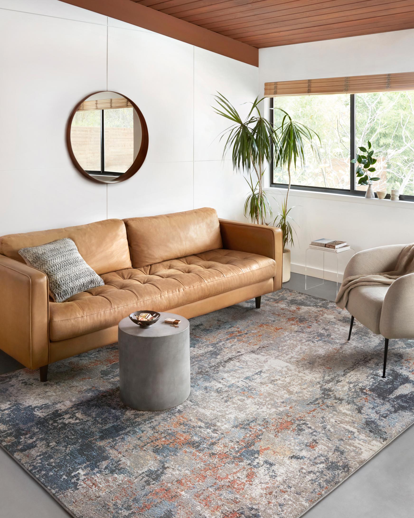 Contemporary abstract rug in silver, blue-gray and apricot, shown under a living room sofa.