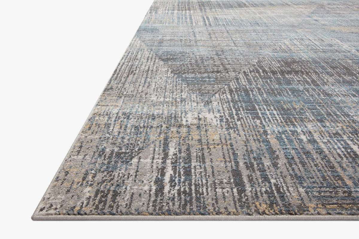 Corner view of granite and mist area rug with textured abstract pattern
