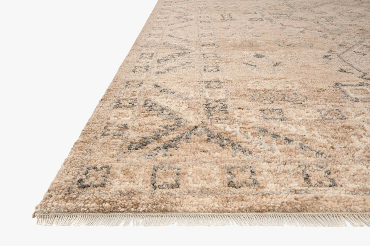 Corner view of sand-toned hand-woven rug with geometric pattern and short fringe