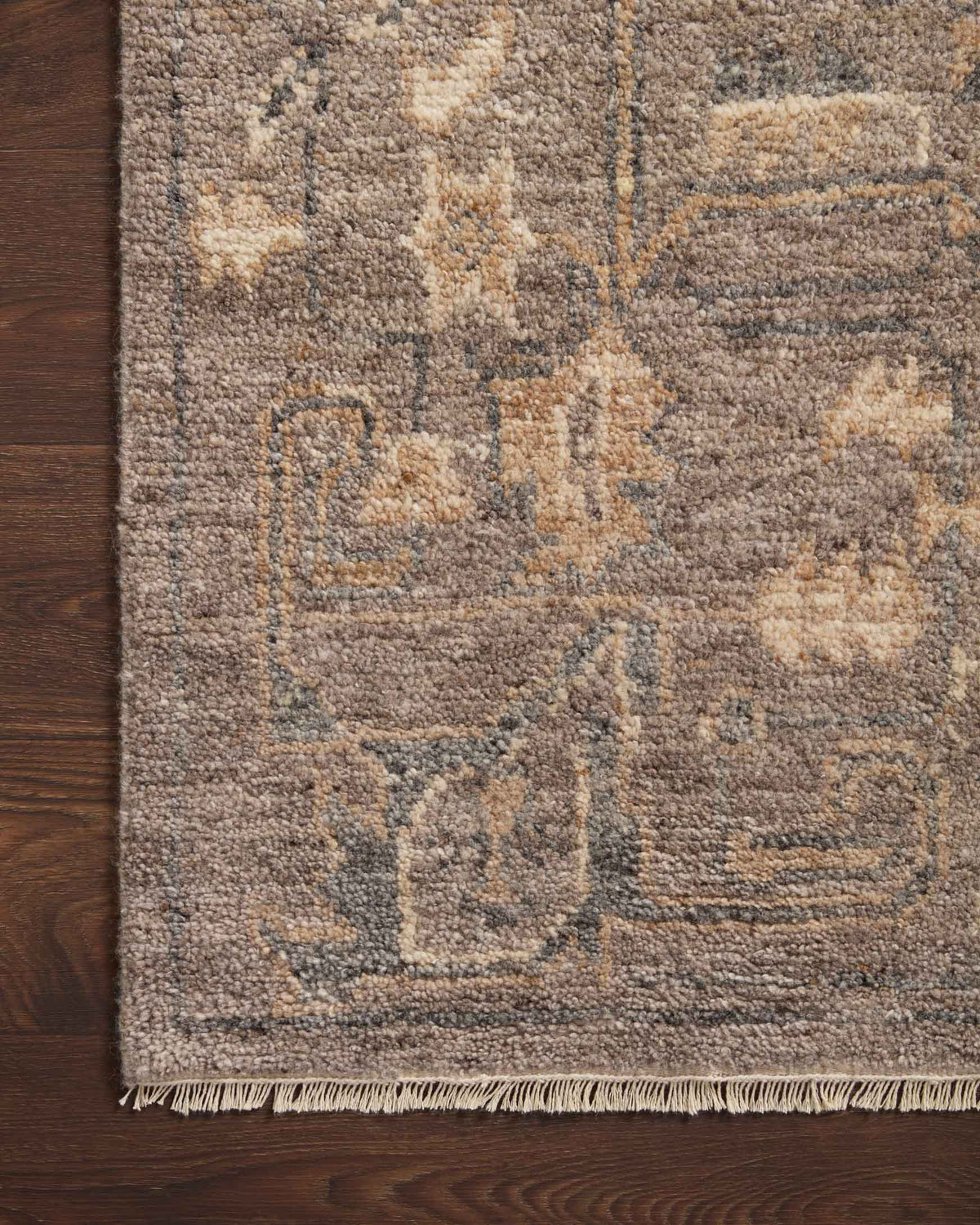 Close-up of hooked rug texture with muted geometric motifs in tobacco and mocha