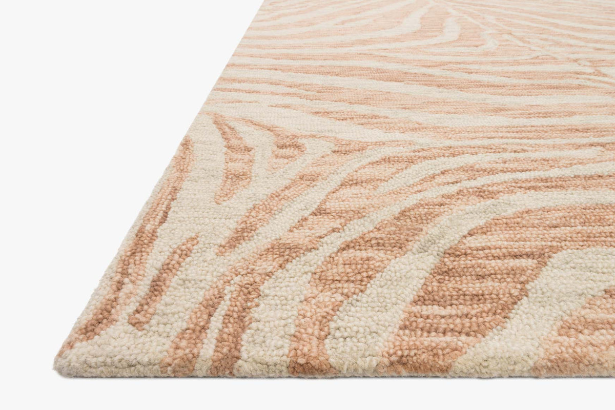 Corner view of hooked rug with blush and ivory abstract stripe motif, textured pile.