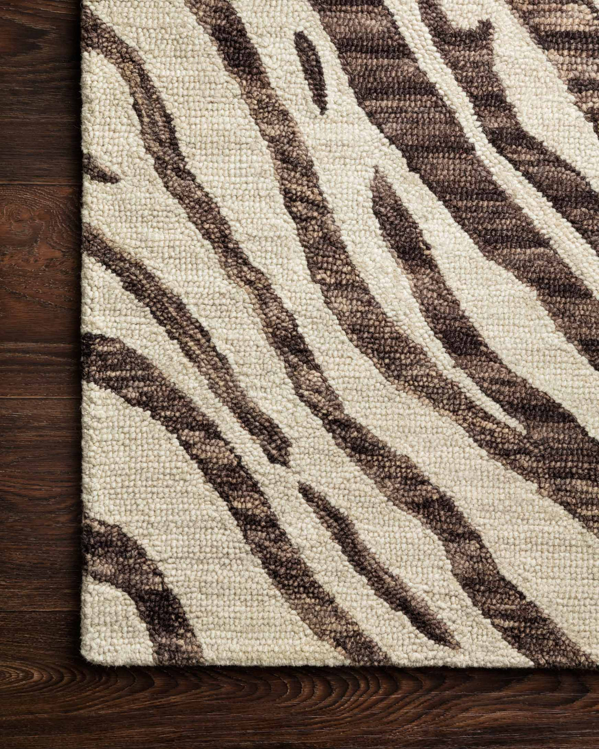 Contemporary hooked rug detail on wooden floor, ivory texture with dark brown curved stripes