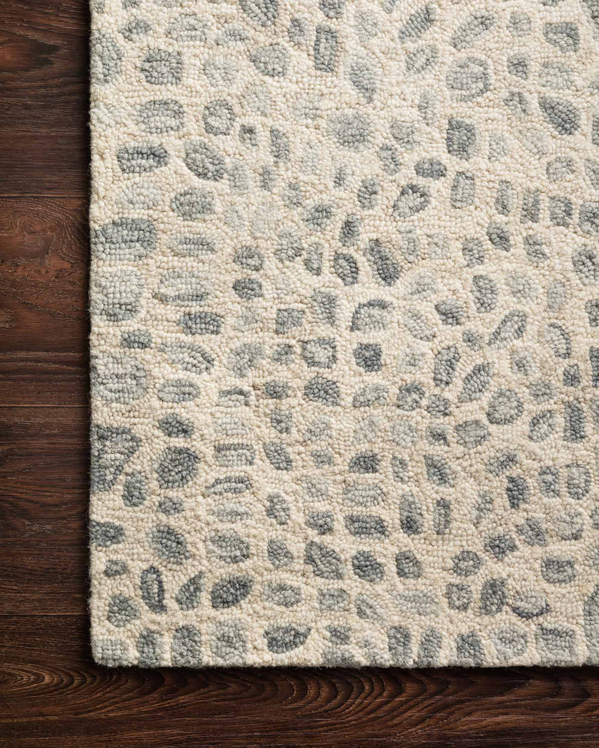 Contemporary hooked rug corner with short pile; silver-grey and ivory abstract pattern.