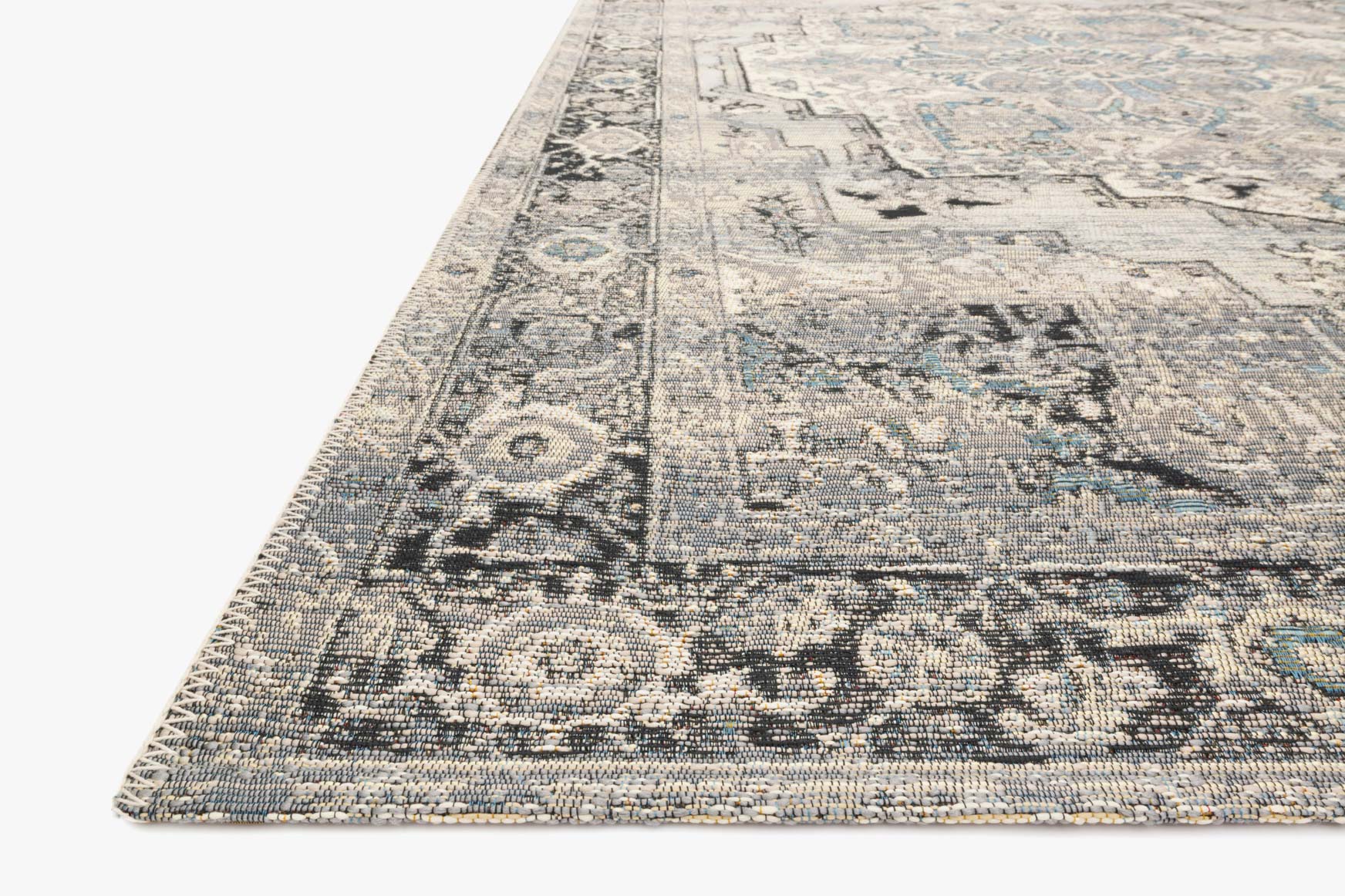 Grey and blue patterned rug corner detail, flat weave texture visible