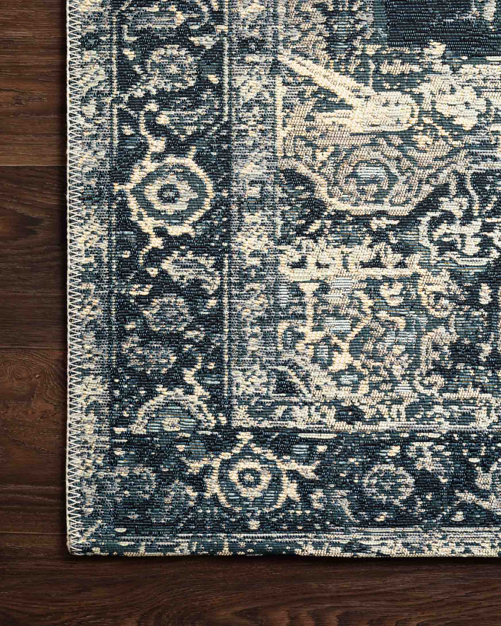 Indoor/outdoor rug detail, dark blue and cream textured medallion pattern edge.