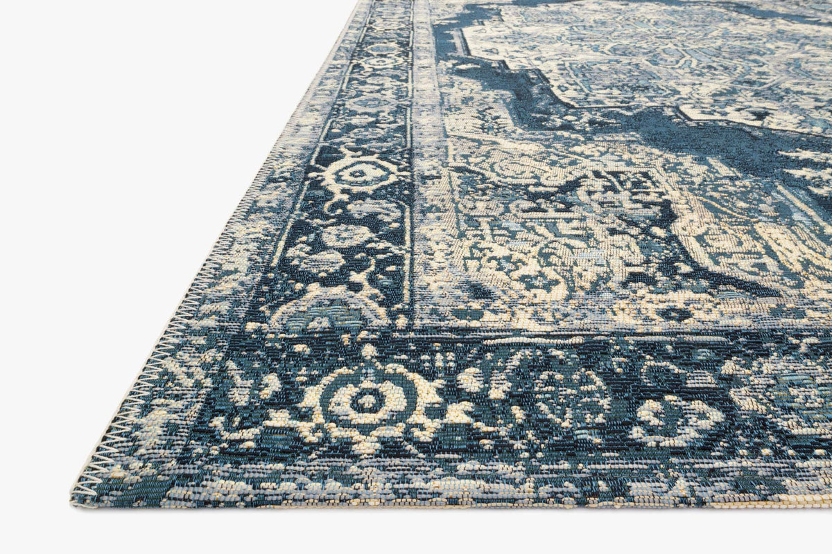 Indoor/outdoor power loom rug corner view, dark blue and cream ornate pattern.