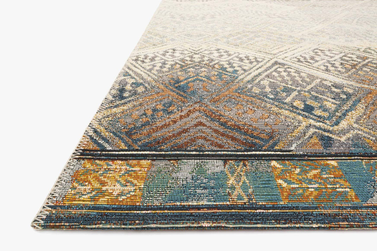 Indoor/outdoor power-loomed rug with ivory base, blue and orange tribal motifs, angled view