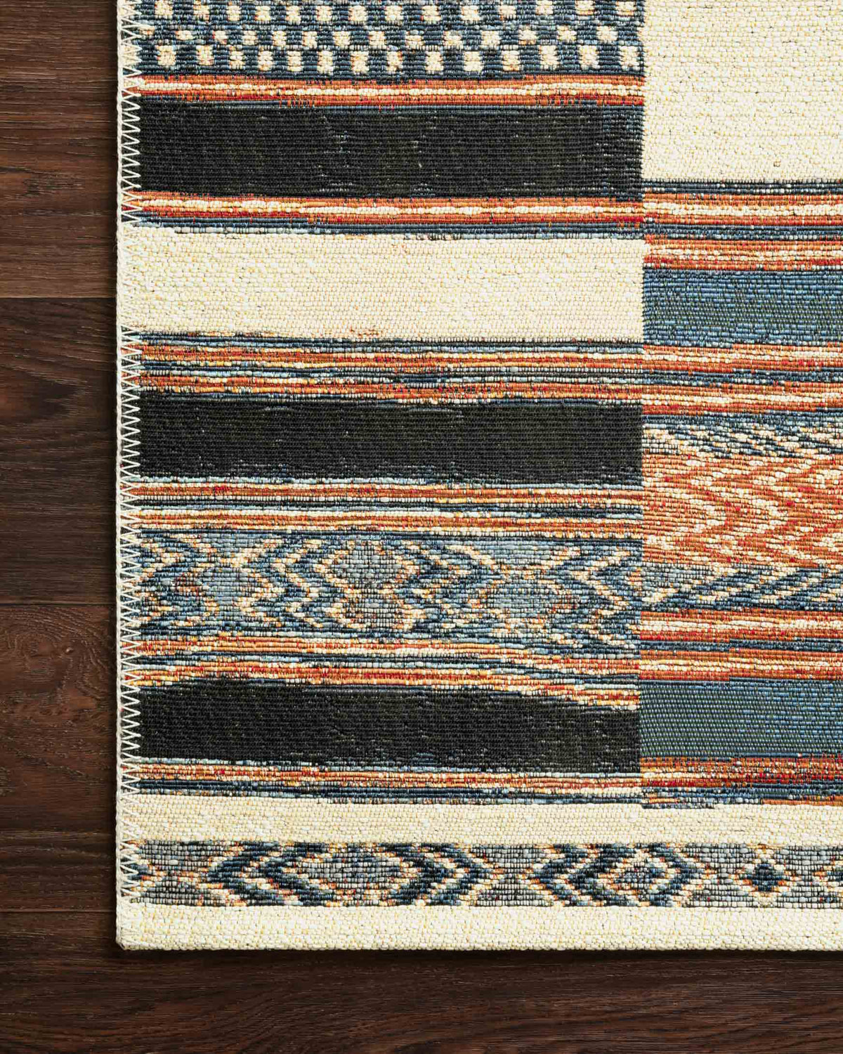 Ivory geometric rug edge with blue, navy, and orange stripe pattern