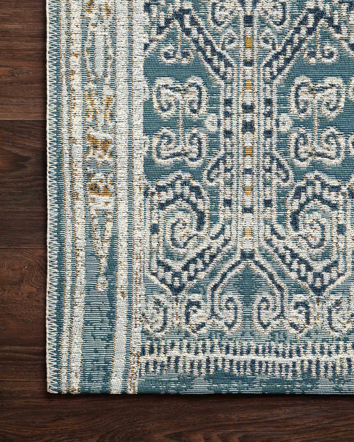 Blue indoor/outdoor rug close-up showing intricate medallion pattern and striped edge