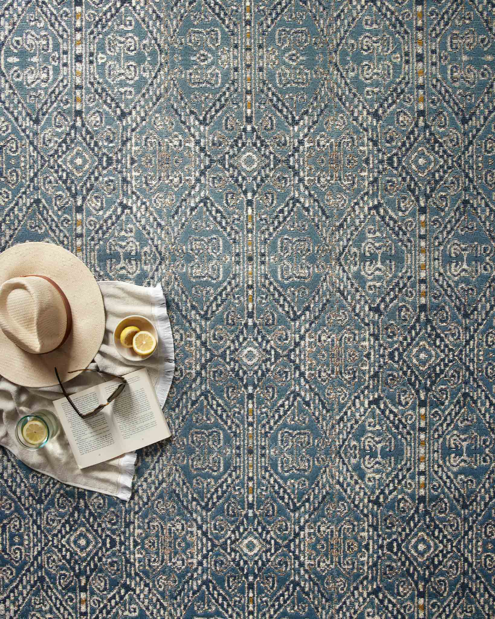 Blue indoor/outdoor rug close-up with repeating geometric pattern and cream accents