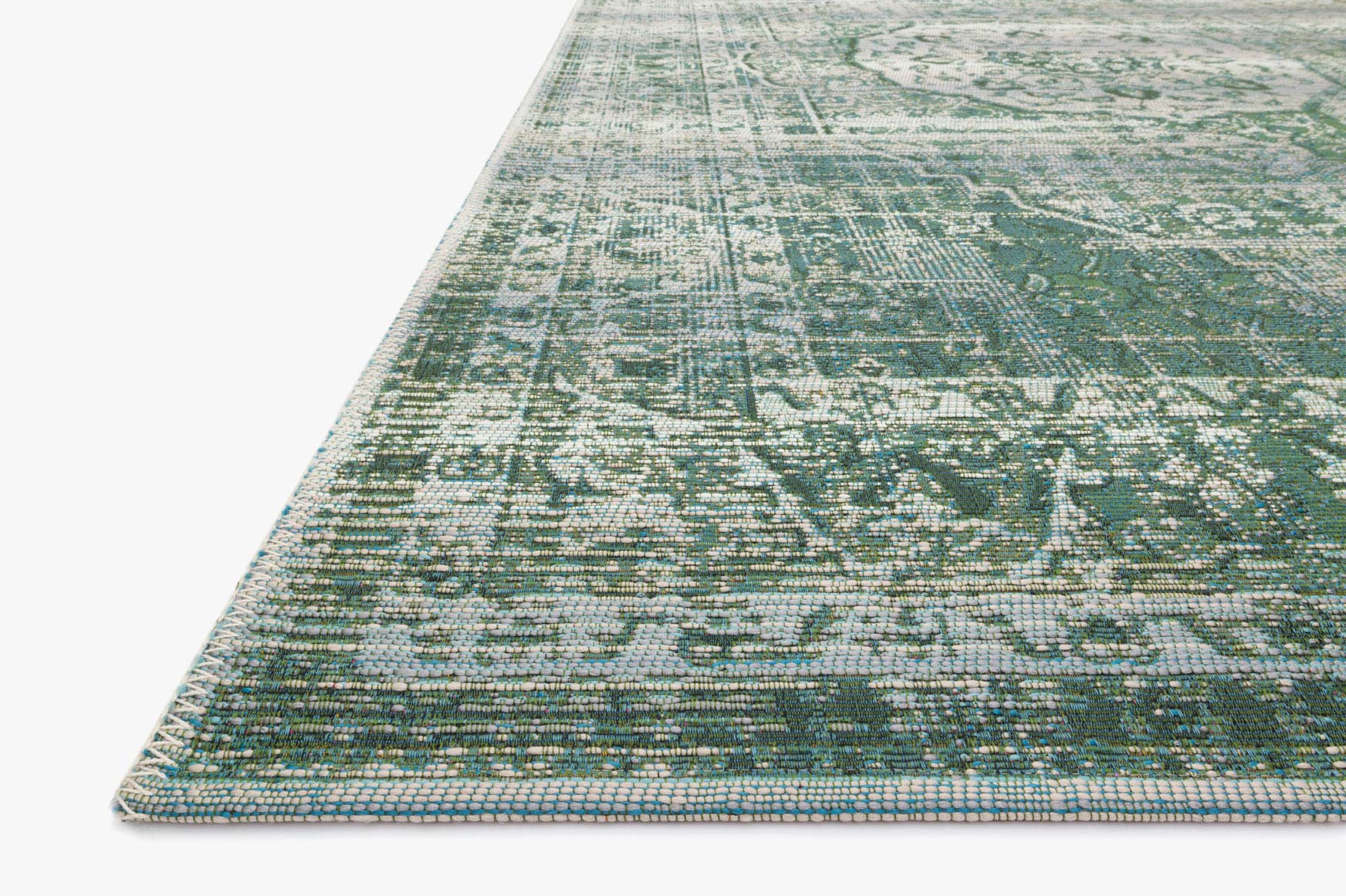 Edge view of green and mist power-loomed rug with dense abstract texturing