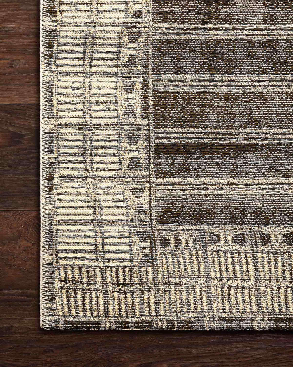 Charcoal and ivory rug border close-up with woven grid texture and stripe bands