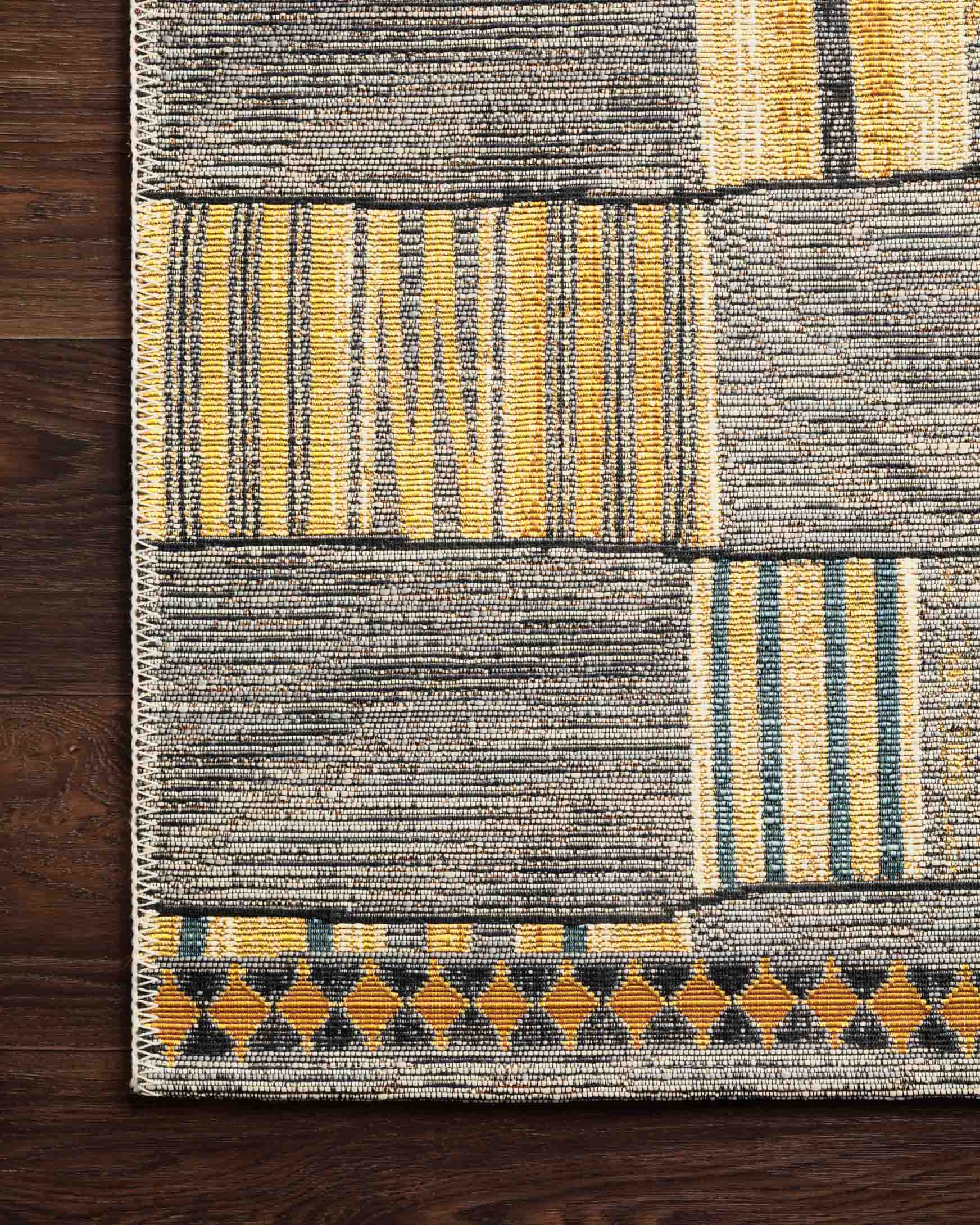 Rug corner with textured gray weave, yellow panels, and black patterned border trim