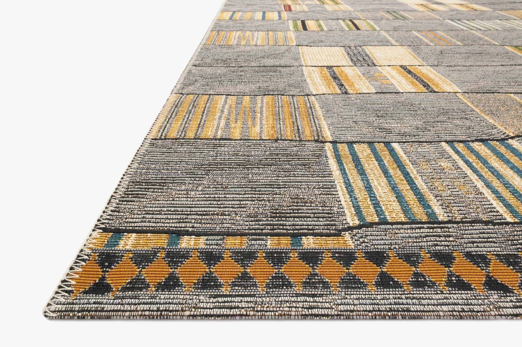 Angle view of gray woven rug with geometric blocks, yellow stripes, and blue accents