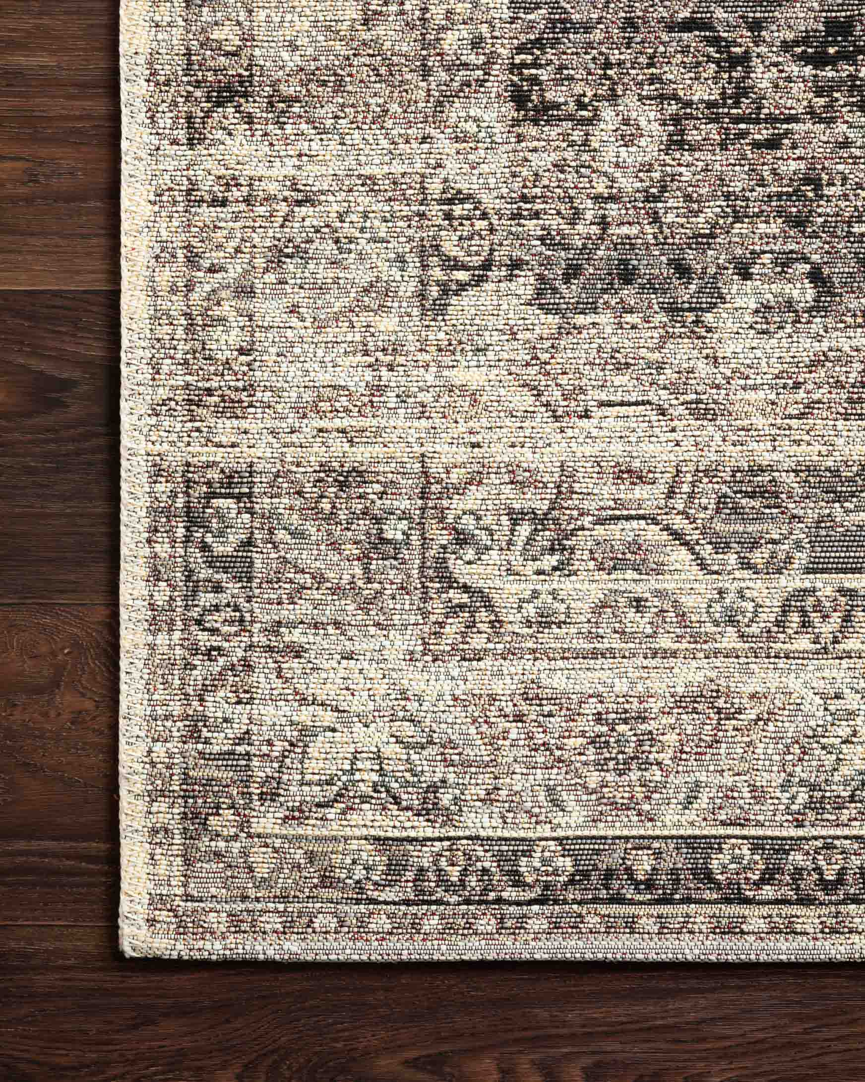 Stone-and-ivory rug surface with detailed distressed geometric motifs and woven texture.