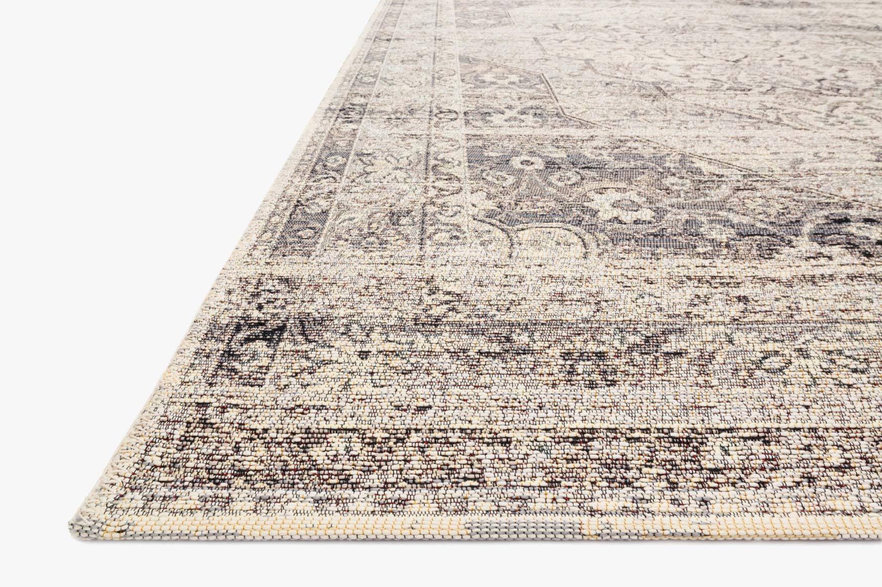 Stone-and-ivory rug corner with patterned edge and flat woven texture.