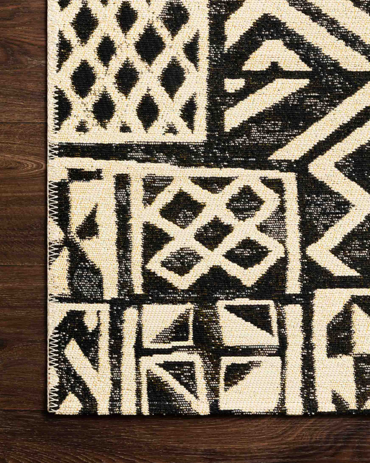 Ivory and black geometric rug corner detail with diamond motifs and zigzag lines.