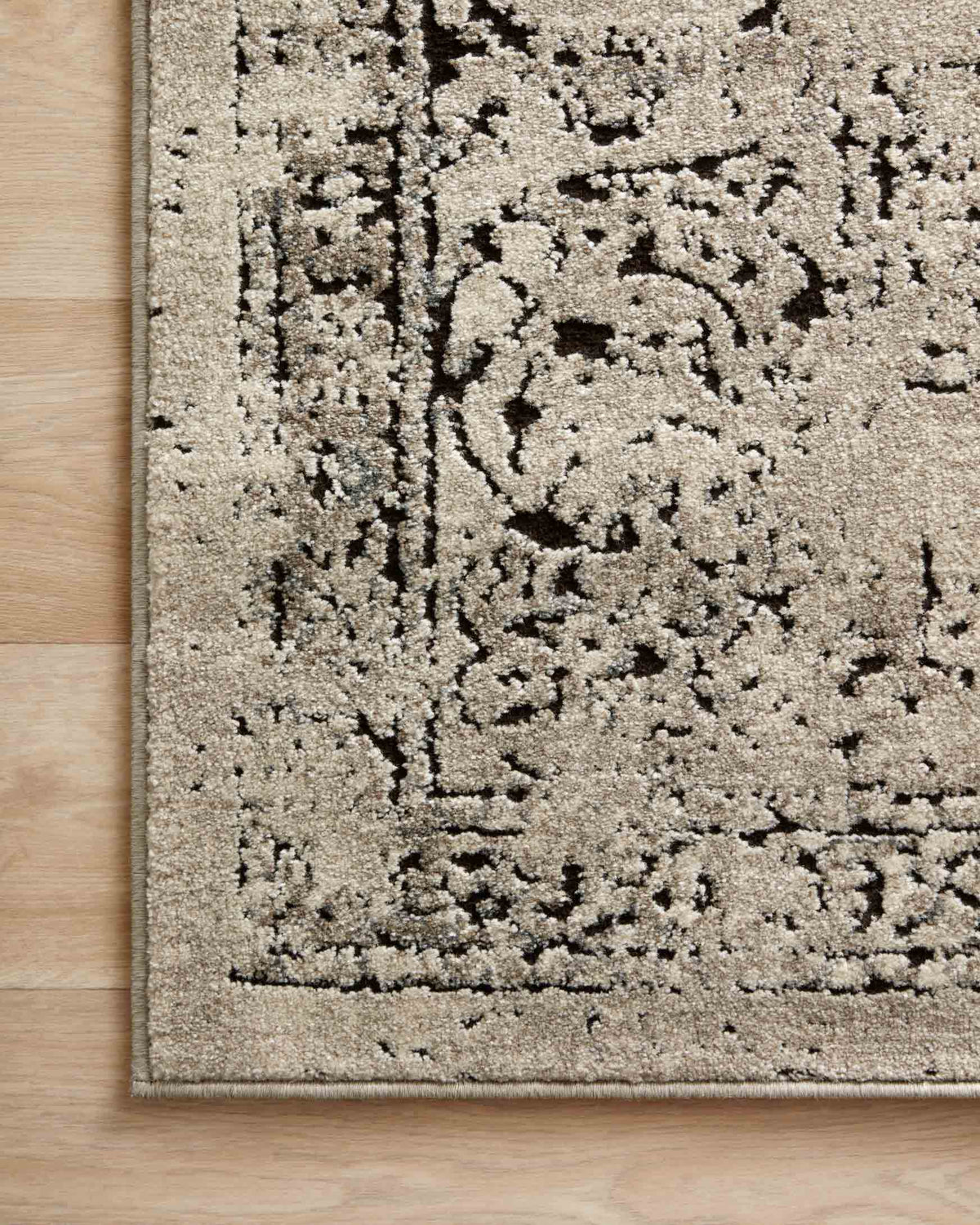 Close-up stone and charcoal rug with dense distressed motif and low textured pile