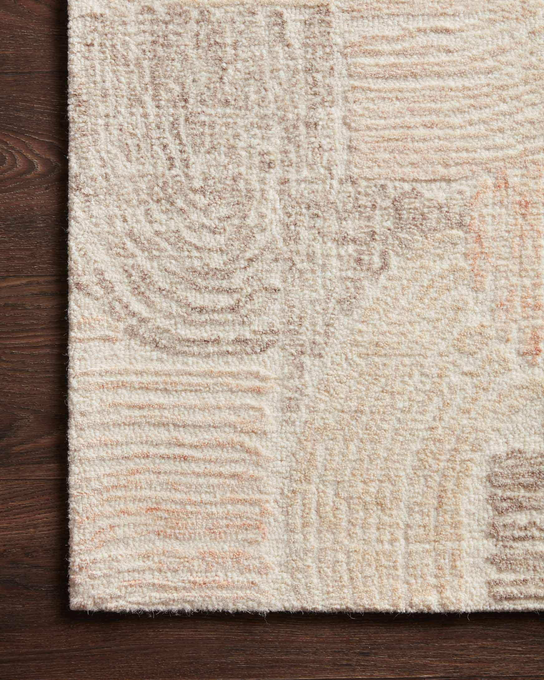 Close-up of abstract hand-tufted rug texture in light cream with peach and tan lines