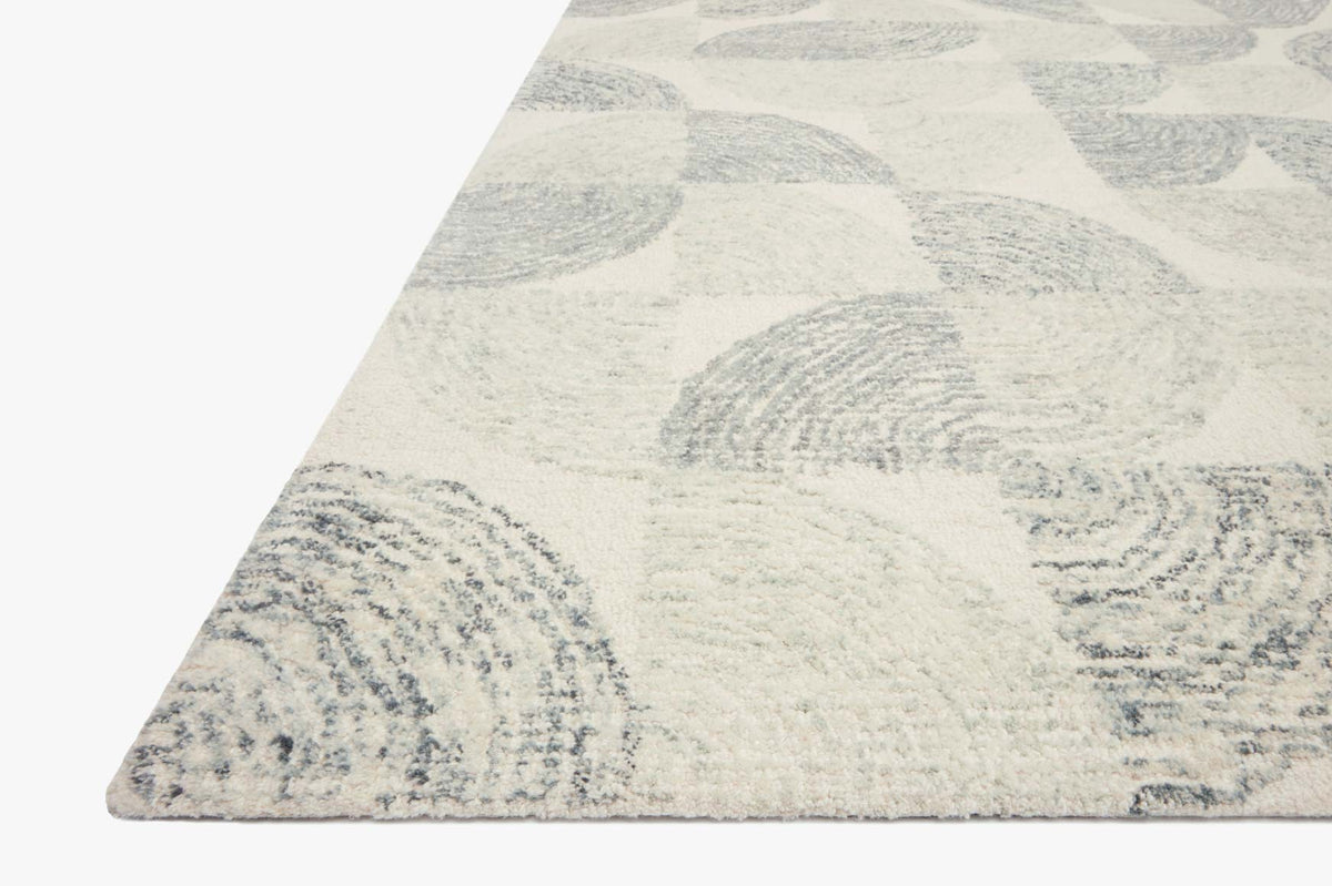 Hand-tufted rug corner view with slate-blue circles and textured marks on cream