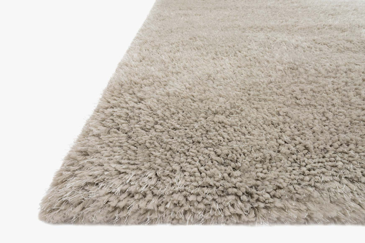 Grey shag rug corner close-up showing fluffy tufted pile texture.