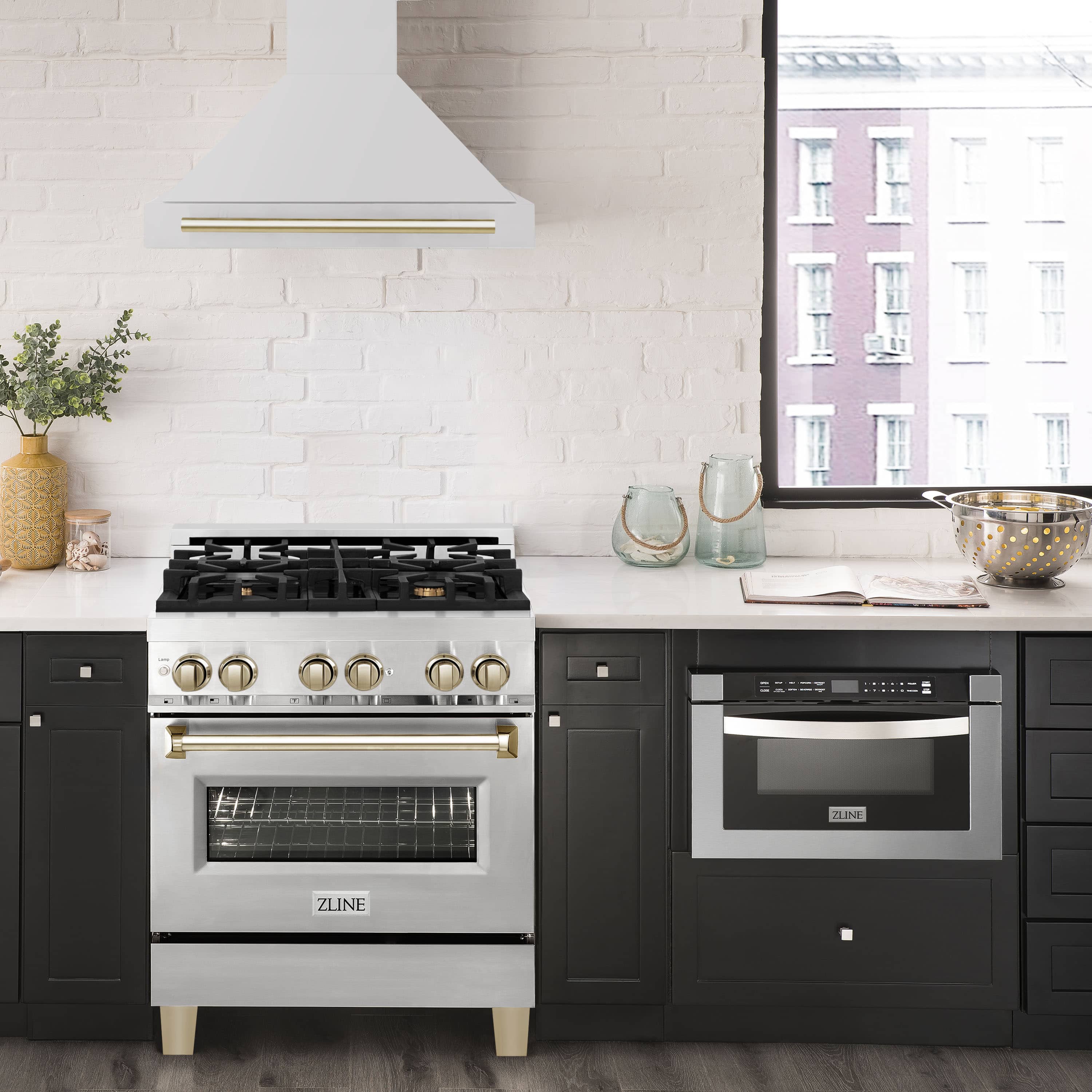 Wall-mount range hood in stainless steel with gold handle above a black gas range.