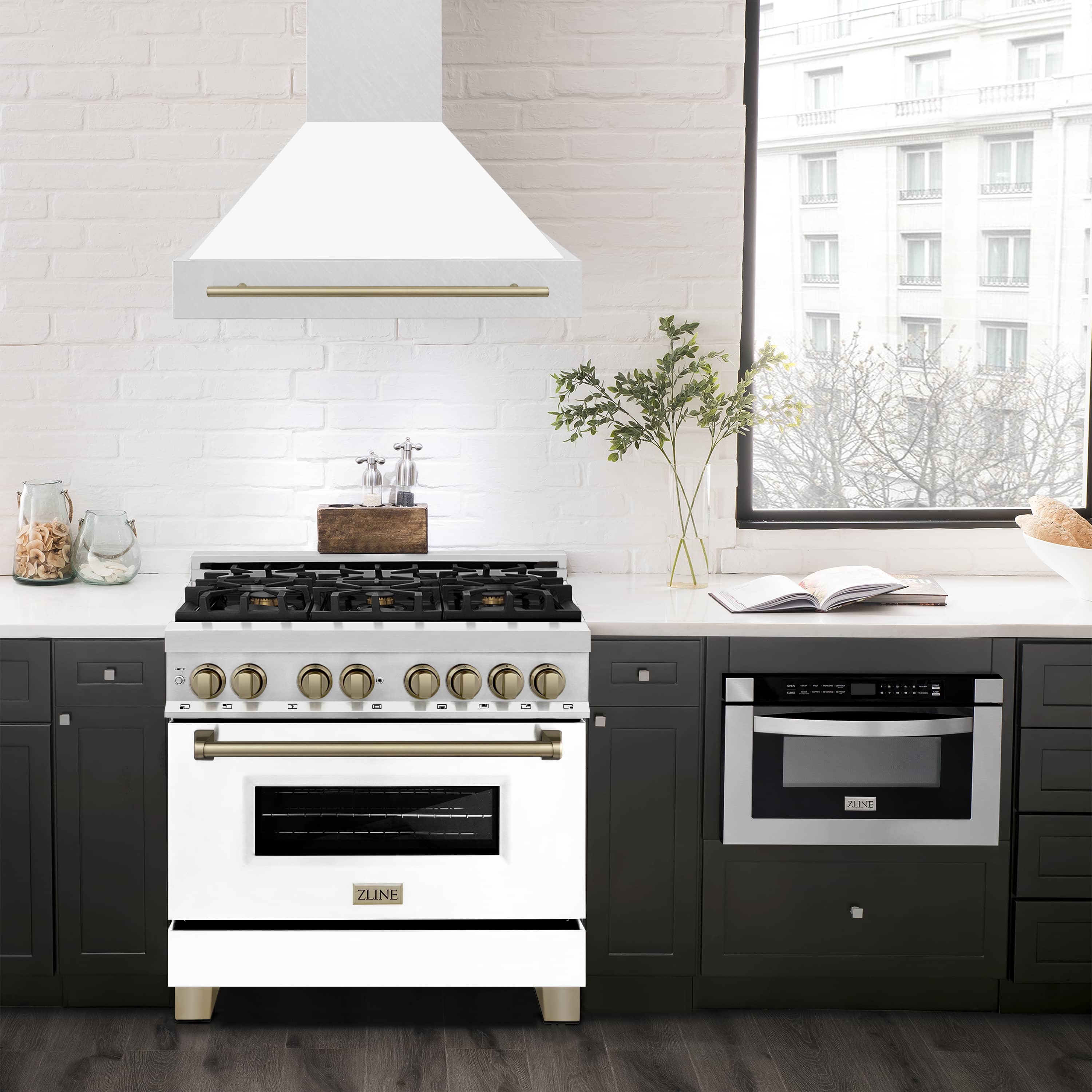White matte wall mount range hood with champagne bronze handle bar above a gas range.